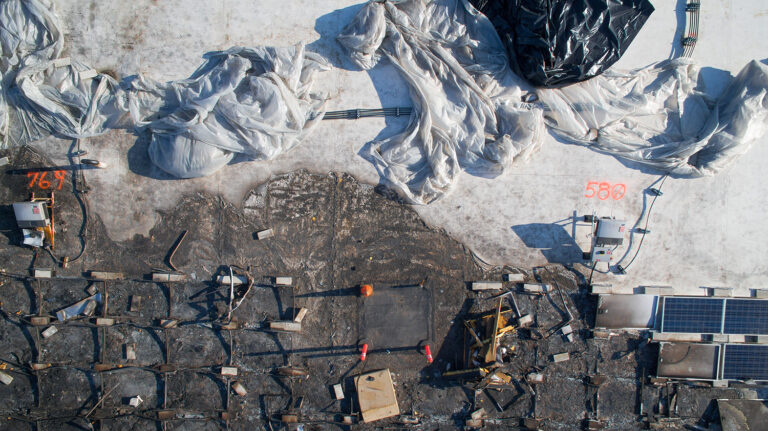Close inspection pass over rooftop solar panels showing fire damage