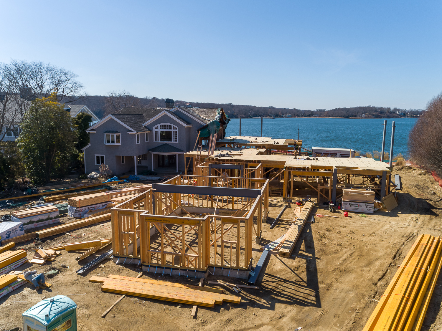 Aerial of timber framing under construction beside an existing waterfront home