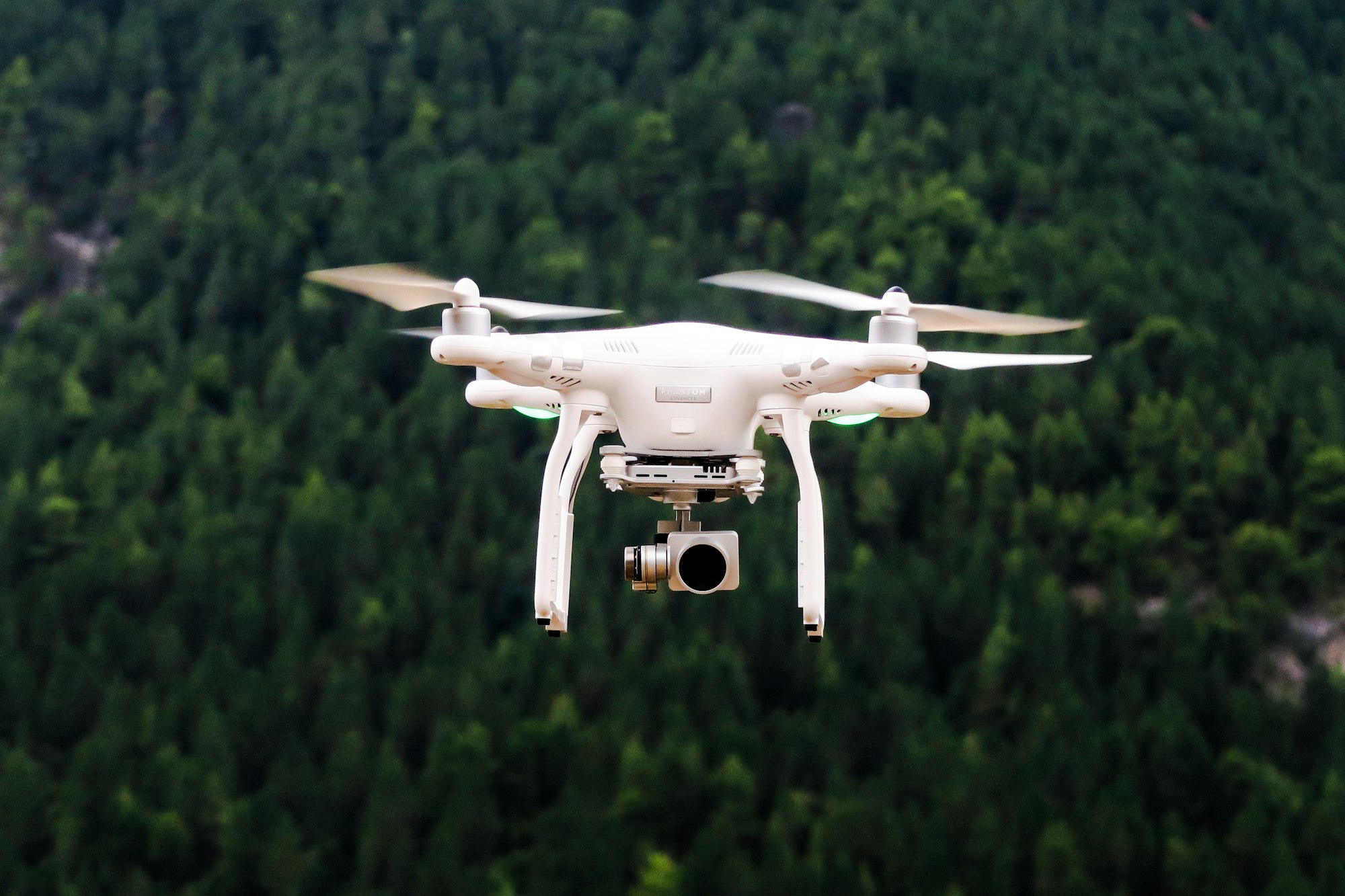 Camera drone in flight capturing aerial video over a forest