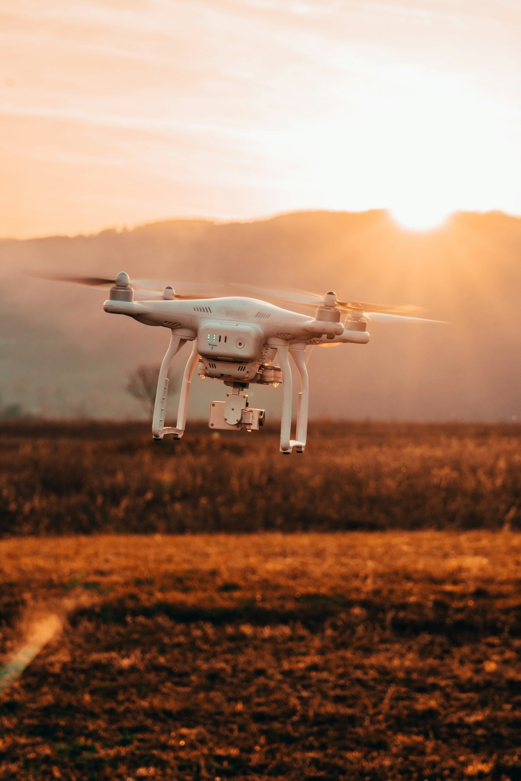 Phantom 4 drone hovering over open land at sunset during an aerial video shoot