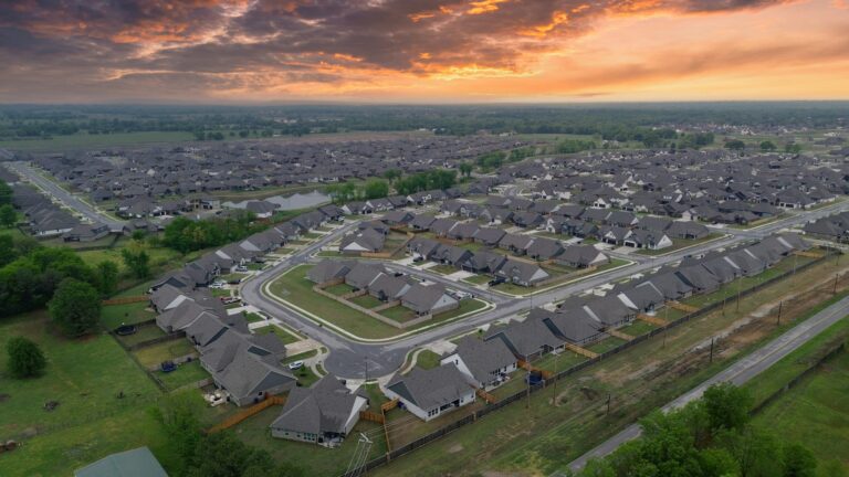Drone photo of a residential neighborhood at sunset, showing homes, streets and open land