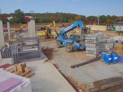Precast concrete wall sections braced on the slab with a telehandler alongside