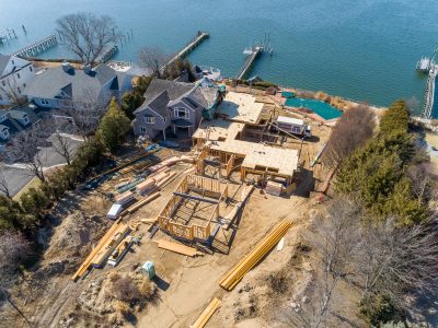 Drone view of timber framing rising at the water’s edge with dock construction below