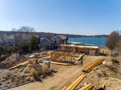 New home framing on the shoreline with open water behind the structure