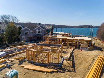 Aerial of timber framing under construction beside an existing waterfront home
