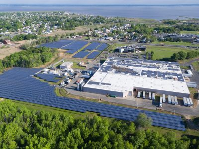 Drone view of a solar field next to an industrial facility